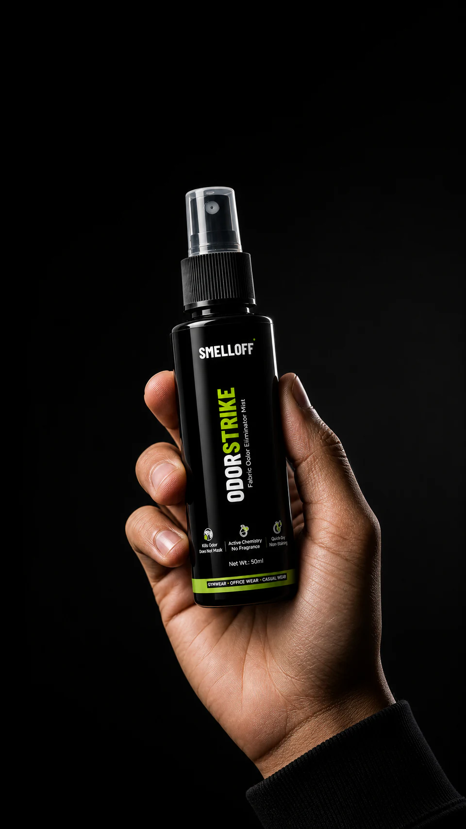 A hand holding the ODORSTRIKE 50ml fabric odor spray bottle against a black background